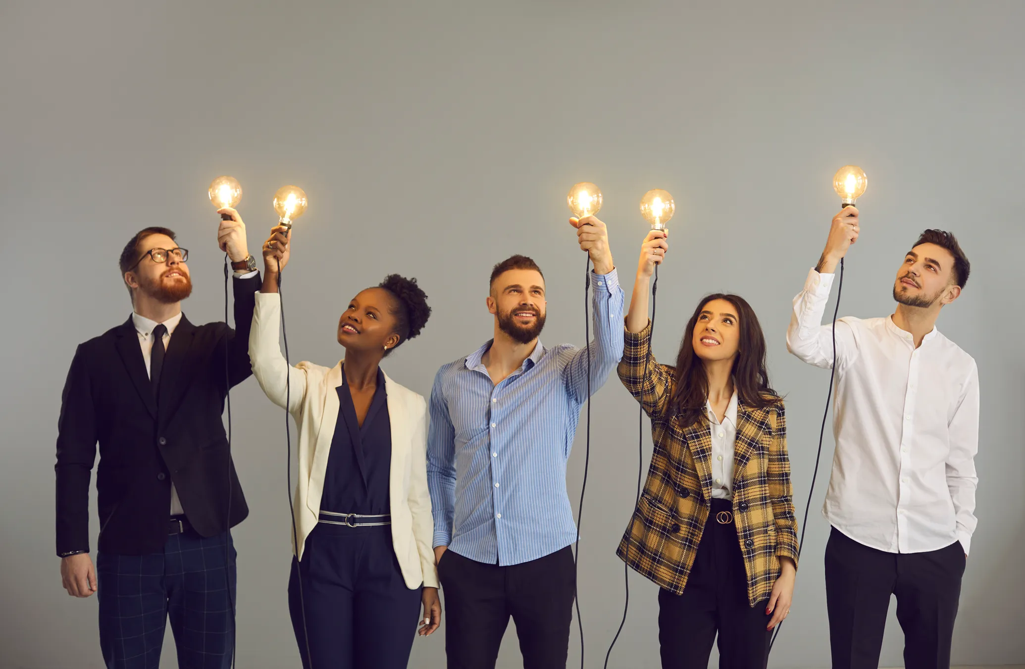 Group of happy diverse business people standing in studio and holding glowing light